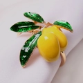 Detalle de cerca del servilletero de limón dorado con frutas amarillas y hojas verdes - Limón Dorado