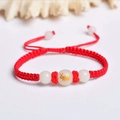 Close-up of handmade red braided bracelet with luminous white beads and golden rabbit charm - Red Rope [Rabbit]