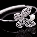 Détail d'un bracelet papillon argenté avec zircons étincelants et une perle blanche chic - Argent