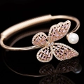 Bracelet manchette papillon or rose avec pierres roses et détail de perle blanche en gros plan - Or rose + Rose
