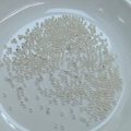 Macro shot of silver small cylindrical crimp beads for jewelry making in a white ceramic dish - Silver Plated (Color Retention)
