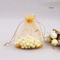 Detail of gold organza jewelry pouch with star and moon print filled with round beads - Gold