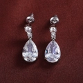 Detailed view of silver teardrop earrings with pear-cut cubic zirconia on red silk - White