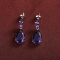 Macro detail of silver drop earrings featuring purple pear-cut and round cubic zirconia - Purple