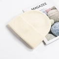 Thick ribbed knit beanie in cream white with a rolled cuff, styled on a magazine - Cream