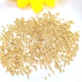 14K gold plated crimp beads for DIY jewelry making scattered on a white ceramic plate - 2.5mm (10g Approx 420pcs) / 14k Gold Color Preserved