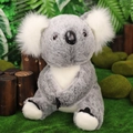 Morbido peluche di koala grigio e bianco seduto in una calda ambientazione forestale - Grigio