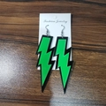 Fashionable green acrylic lightning bolt earrings with black edges on wooden background - Green
