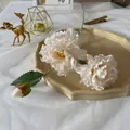 Detailed close-up of realistic cream peony silk flowers on elegant ceramic tabletop setting - Off White
