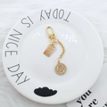 Detail of gold keychain with fine gold bar pendant and vintage coin charm on plate - Gold Bar And Coin Combination Style (3087-3)