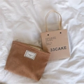 Close-up of brown corduroy cosmetic bag with TIME TO PARTY label on white fabric - Camel