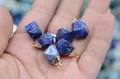 Close-up of a hand holding a raw faceted blue lapis lazuli pendant with gold clasp hook - Lapis Lazuli