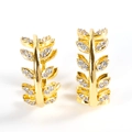 Elegante gouden blad oorringen met glinsterende zirkonia stenen op een witte achtergrond - Legering Goud