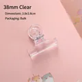 Clip trasparente da 38mm per fogli e snack mostrata su uno sfondo di carta rosa - Medio (38mm)