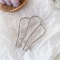 Épingle à cheveux en métal argenté en forme de M sur fond blanc minimaliste - Argenté