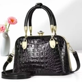 Detail of black crocodile embossed patent leather handbag with luxury gold hardware - Black