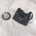 Detalle del bolso tote de lona con estampado de guijarros en blanco y negro sobre cama blanca - Estampado de Leopardo en Blanco y Negro