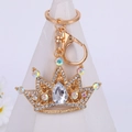Eleganter goldener Kronen-Schlüsselanhänger mit Strasssteinen auf weißem Ständer - Weißer Edelstein-Stil