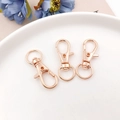 Trois fermoirs mousquetons en or rose avec base pivotante sur une assiette en céramique - 32mm / Or rose