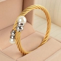 Makroaufnahme einer goldenen verdrehten Armspange mit eleganten weißen Perlen - Goldenes Kabel/Stahlenden