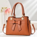 Detailed view of brown tote bag with geometric embossing and large bow accent - Earthy Yellow