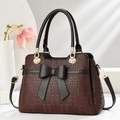 Deep brown women's handbag with bow decoration and geometric pattern in a studio setting - Coffee