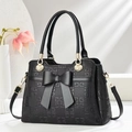 Elegant black handbag with bow decoration and geometric pattern shown in a minimalist setting - Black