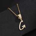 Macro shot of gold G letter pendant with zircon inlay on black leather background - Letter G