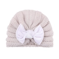 Close-up of baby knit hat showing chunky beige knit texture and large white bow detail - Off-white
