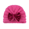 Detail of rose pink baby knit turban hat featuring a large deep red velvet bow decoration - Rose Red