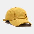 Detail of mustard yellow baseball cap showing vintage distressed holes and torn cotton fabric - Yellow