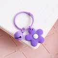 Pastel purple keychain accessory with metal ring, bell, and floral charm on a notebook - Purple Flower With Bell