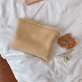 Detalle de neceser beige de lana de cordero sintética con textura suave y accesorios - Camello Claro