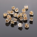 Macro detail of 18k gold metal core and silicone earring backs on a dark reflective surface - 18K Gold Plated Silicone Earring Backs