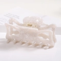 Macro view of a large white acetate hair claw clip with elegant marble texture and gold spring - S141-1 Mother of Pearl White