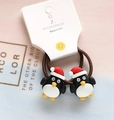 Close-up of brown elastic hair ties with cartoon penguin charms and Santa hats for kids - Cartoon Penguin
