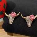 Macro shot of golden bull head brooches with pink roses and white crystals on black velvet - Vintage Bull Head Pink Rose Gold
