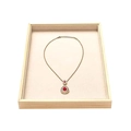 Detailed macro view of a gold waterdrop ruby pendant displayed in a wooden jewelry tray - Flat Tray