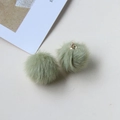 Dettaglio di due ciondoli a pompon verde chiaro con anelli metallici per gioielli fai da te - Verde Grigastro