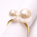Macro shot of matte gold napkin ring featuring two elegant pearls on white fabric - 18+25M Gold Finish White High-Gloss Pearl