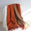Thick dual-color cashmere scarf in dark orange and camel with tassels on a white chair - Orange Red + Camel