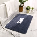 Absorbent dark blue bath mat with white Bath text on a textured bathroom tile floor - 40x60cm / Haze Blue