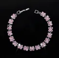 Detailed view of silver-toned flower bracelet with pink zircon petals on a black backdrop - 17.6cm / Pink