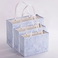Three sizes of blue marble pattern gift bags with white ribbon handles and metal rivets - Blue Marble Rivet Style