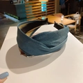 Detailed view of a blue pleated fabric headband featuring a stylish twisted knot design - Blue