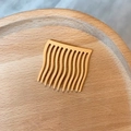 Matter ingwergelber Haarkamm mit Wellenzähnen auf einem natürlichen Holzhintergrund - Matter Kunststoff / Kurkuma