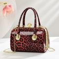 Nahaufnahme der Lackleder-Handtasche mit Leopardenmuster, Perlenverschluss und Kette - Burgunderrot