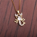 Goldene Skorpion-Halskette mit Zirkon-Steinen auf Holzgrund für Damen - O Kette / Gold