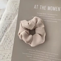 Close-up of beige fabric scrunchie with fine vertical textures on minimalist aesthetic background - Beige