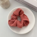 Close-up of knit texture fabric scrunchie in brick red on white ceramic plate - Dusty Pink